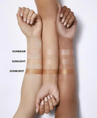 Three arms with different skin tones holding swatches labeled 'Sunbeam', 'Sunlight', and 'Sunburst' on a white background.