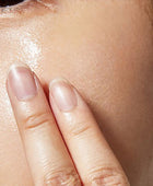 Close-up of a hand applying a skincare product to the face.