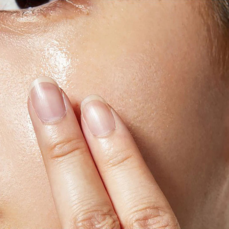 Close-up of a hand applying a skincare product to the face.