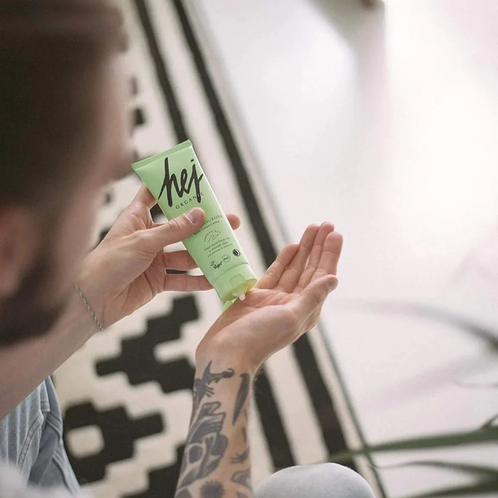 Person holding a green tube labeled 'hej' with a blurred background