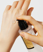 Hand applying COSRX essence to another hand on a light background