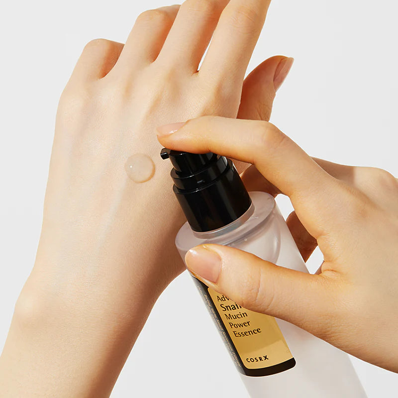 Hand applying COSRX essence to another hand on a light background