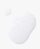 Close-up of a white cream or lotion with bubbles on a light gray background