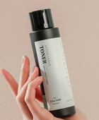 Hand holding a bottle of toner with a beige background