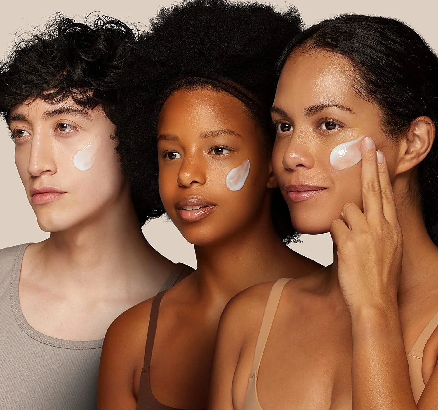Three people with cream applied to their faces against a neutral background