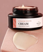 Jar of 'Miracle Youth Cream' with a swatch on a pink background